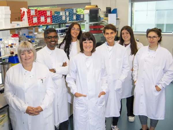 A group of researchers in a research lab is all wearing white lab coats.