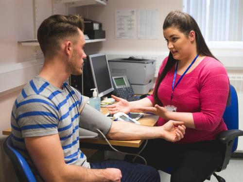 A young man having his blood taken by a female GP