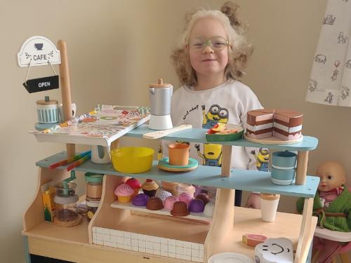 Nicole in her pretend kitchen, smiling
