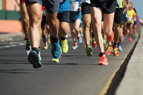A view of the legs and trainers of people running on a paved road.
