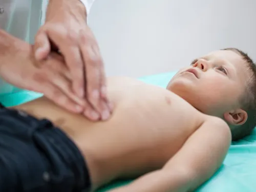 A child receiving an abdominal examination from a doctor.
