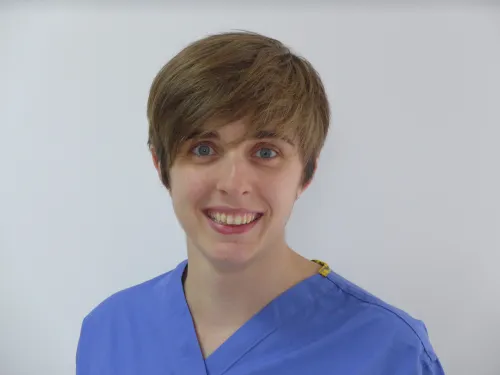 Jess, wearing blue scrubs and smiling at the camera.